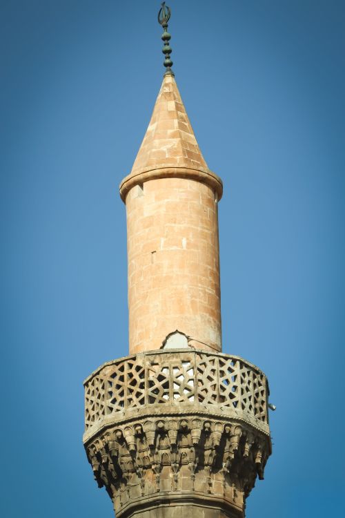 Free Close-up of an ancient minaret with intricate design against a clear blue sky. Stock Photo