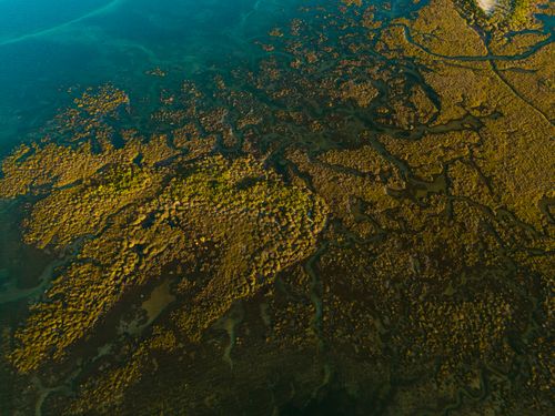 Free Stunning aerial view of vibrant coastal wetlands in Olhão, Portugal, showcasing intricate patterns and rich colors. Stock Photo