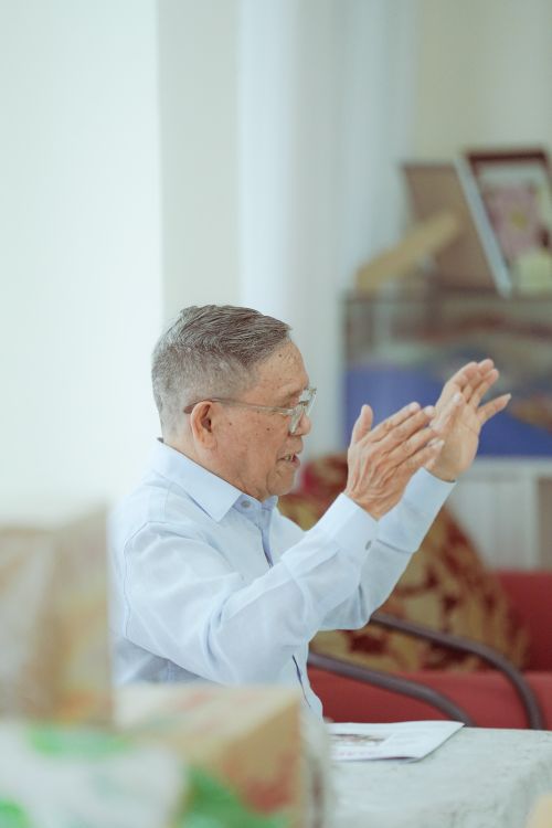 Free Senior man in professional attire gesturing during a conversation indoors. Stock Photo