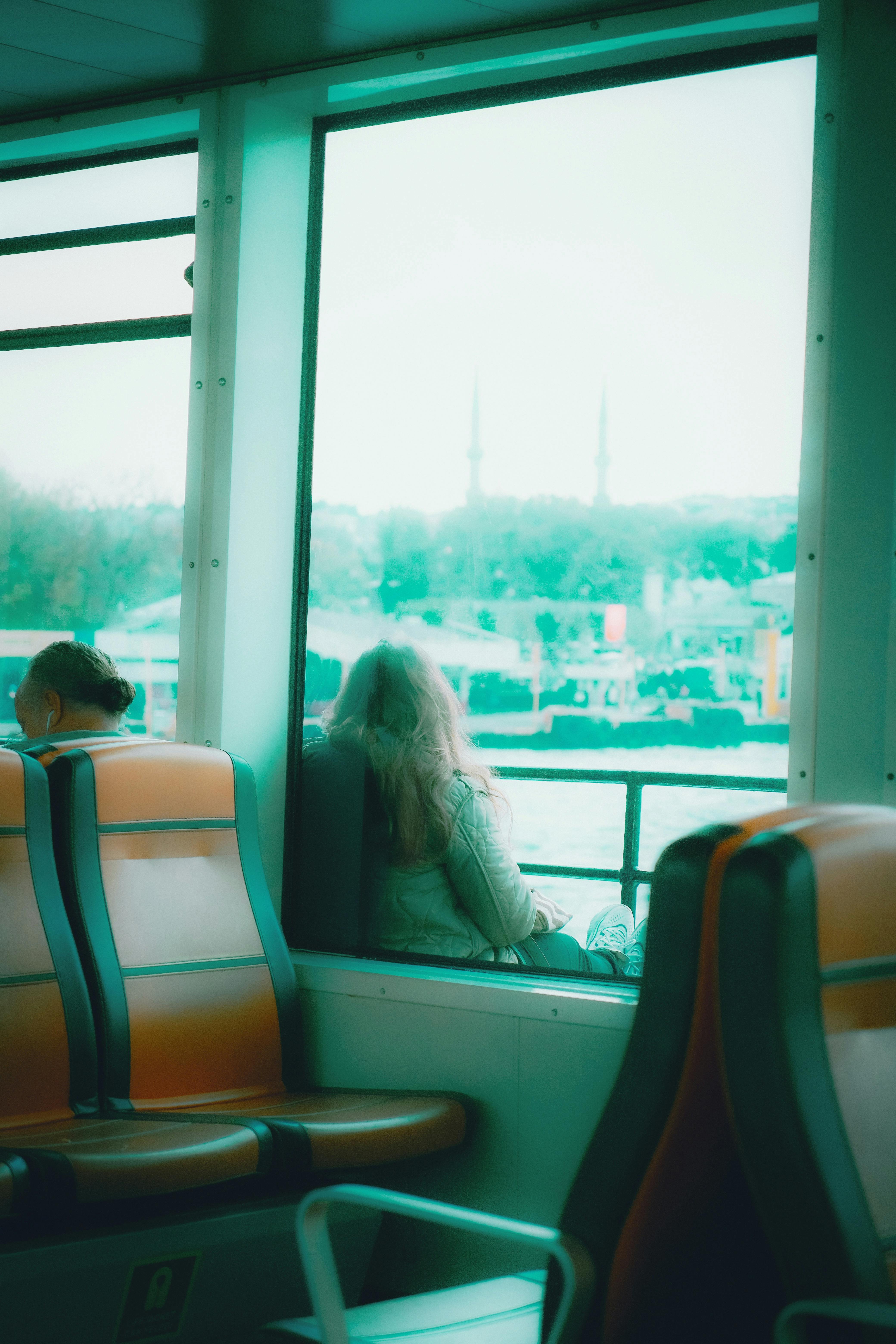 Безкоштовне Двоє людей насолоджуються спокійною поїздкою на поромі з видом на міські пейзажі та самобутню архітектуру. стокове фото