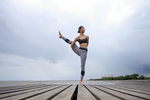 Asian woman performing yoga pose on wooden deck by the sea in Thailand.