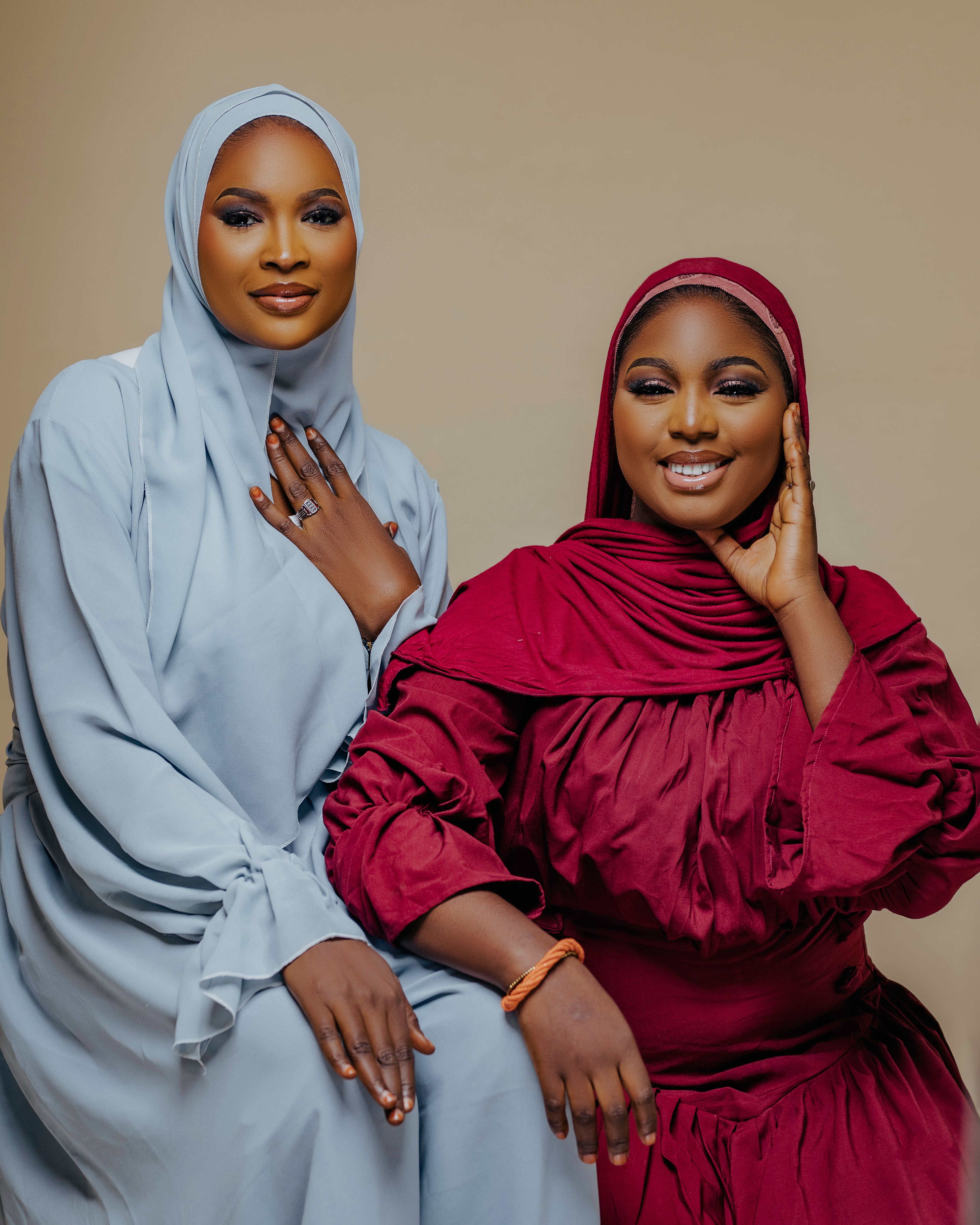 Two smiling women in traditional attire, posing against a neutral background, showcasing cultural elegance.