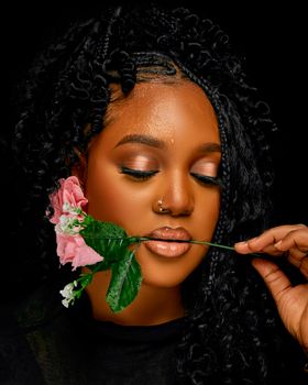 A beautiful portrait of an elegant woman holding a pink rose against a dark background.