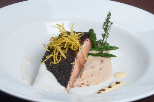 Elegant blackened salmon with asparagus and mashed potatoes on a white plate.