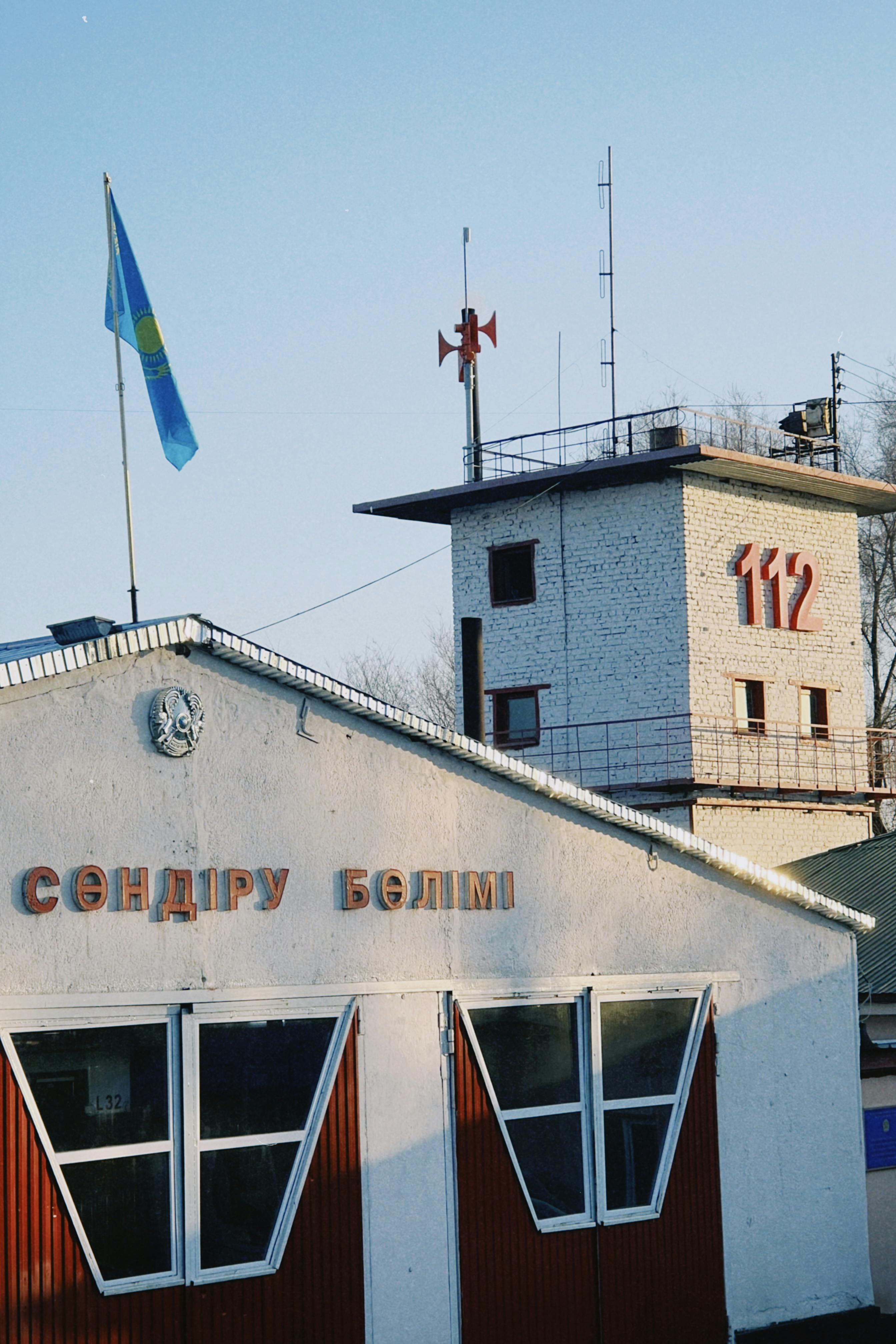 Fire station building with Kazakh flag and '112' signage in Konaev, Kazakhstan.