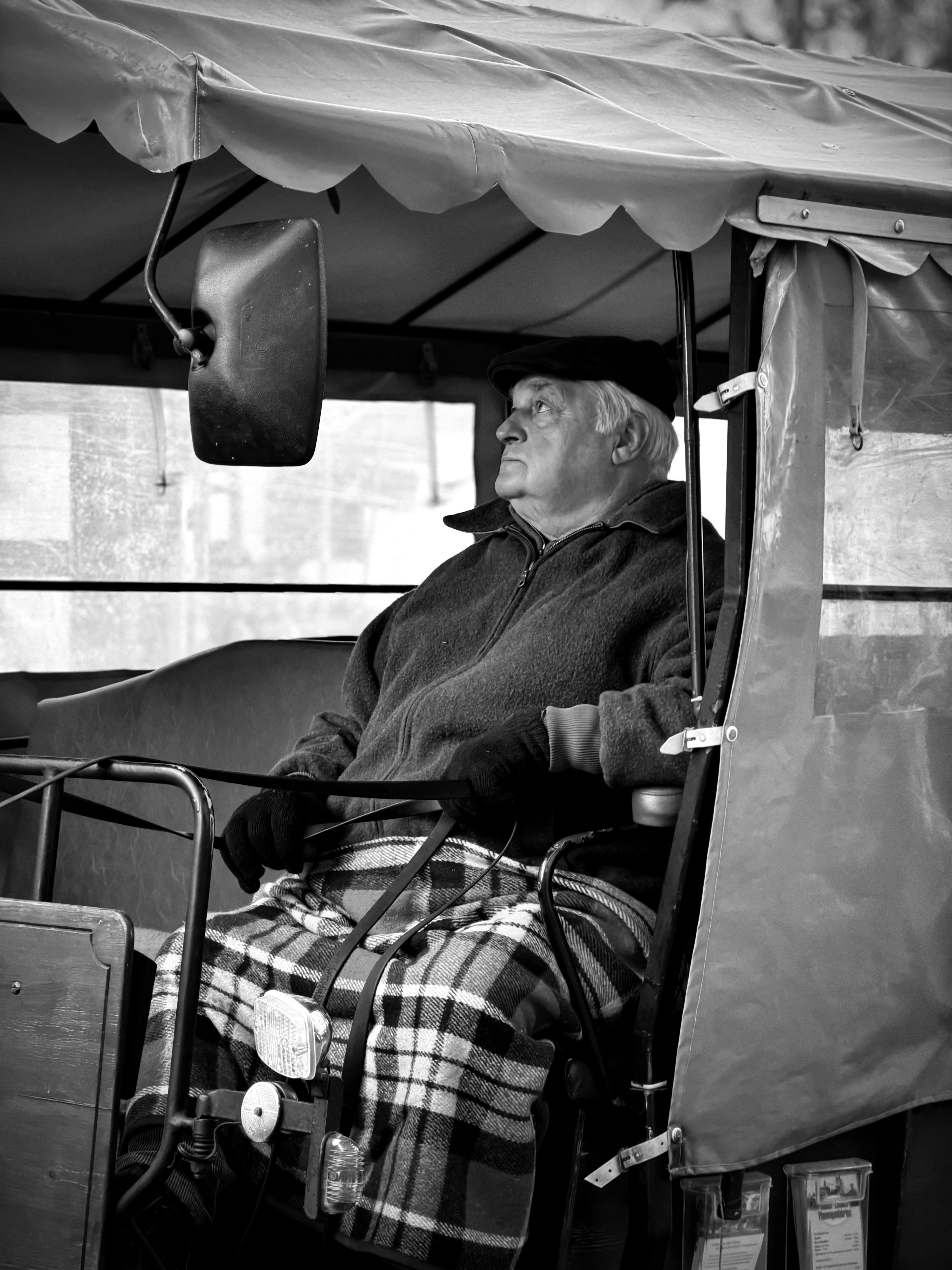 Black and white photo of an elderly man resting in a horse carriage in Wernigerode, Germany.