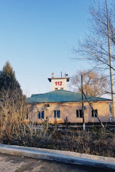 Здание пожарной части с номером «112» на вышке в Конаеве, Казахстан, в окружении голых зимних деревьев.