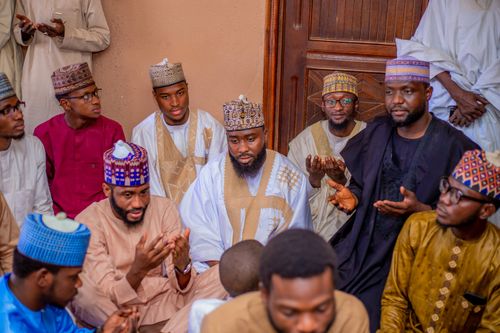 Free A group of African men in traditional attire are gathered indoors for prayer. Stock Photo