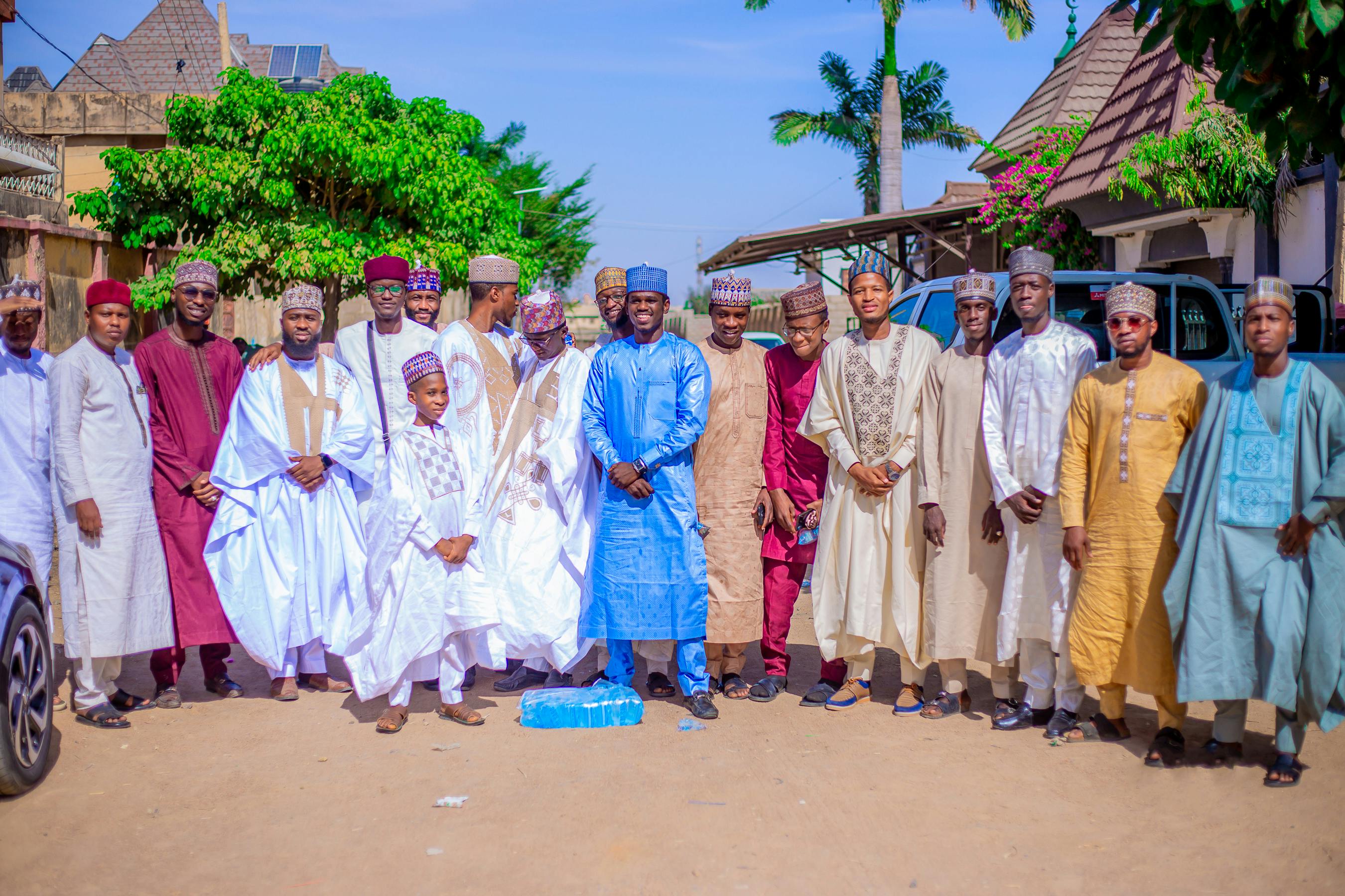 Ücretsiz Güneşli bir havada, canlı renklerde geleneksel Afrika kıyafetleri giymiş bir grup erkek açık havada poz veriyor. Stok Fotoğraflar