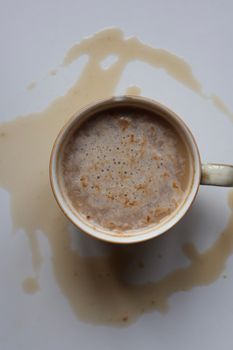 Top view of a coffee cup with spill stains on a white background, creating an abstract design.