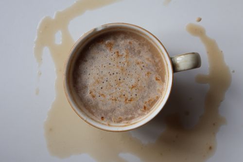Free Coffee cup with spilled drink on white background in top-down view. Stock Photo