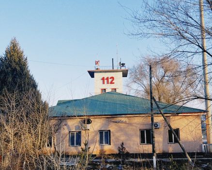 Fire station building with tower and 112 sign in winter, Konaev, Kazakhstan.