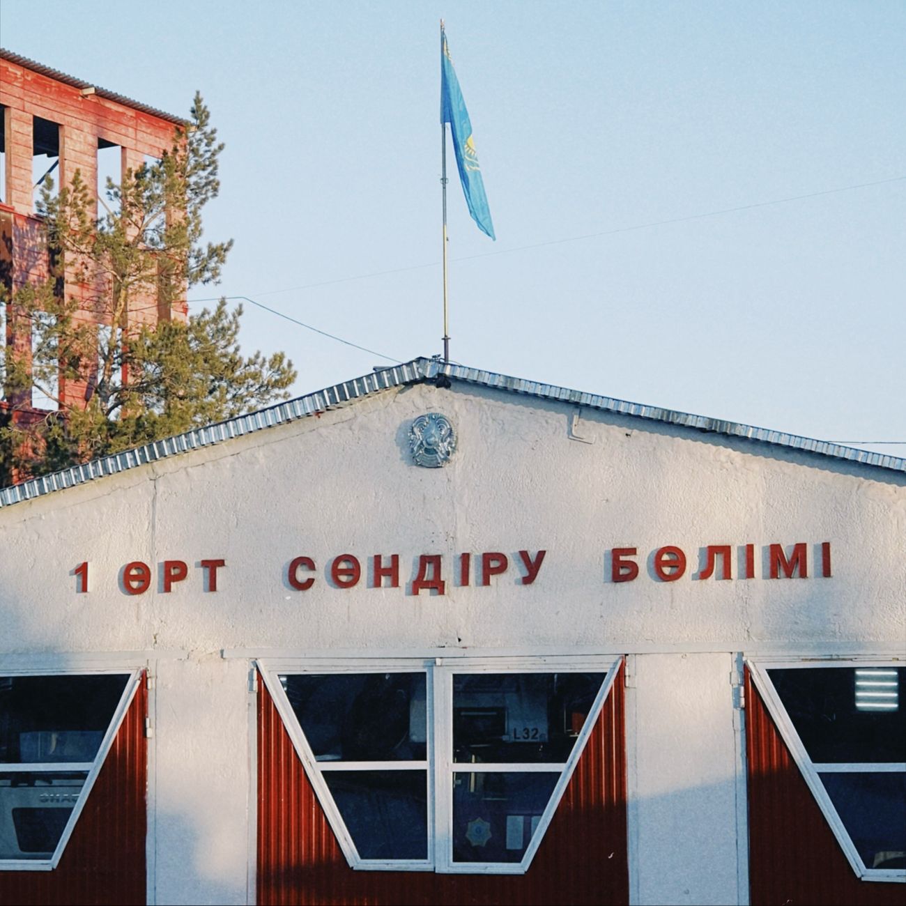 Fire station building in Konaev, featuring Kazakh flag and signage, captured in daylight.