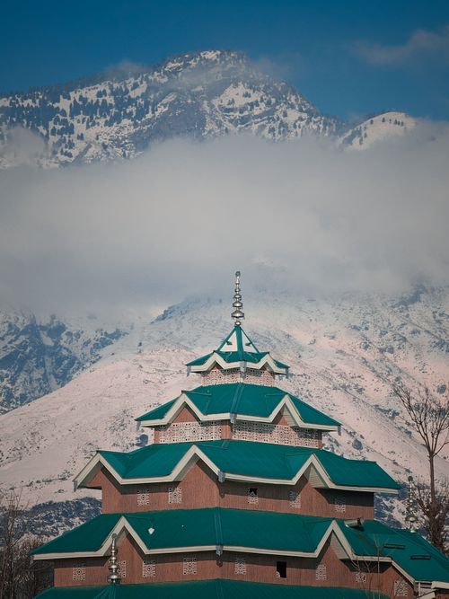 Free A beautiful temple set against the backdrop of snow-covered Himalayan mountains under a blue sky. Stock Photo