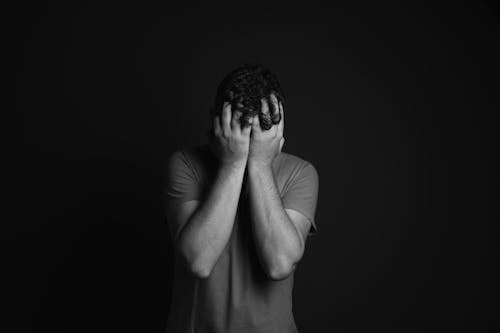 Gray scale Photo of Man Covering Face With His Hands