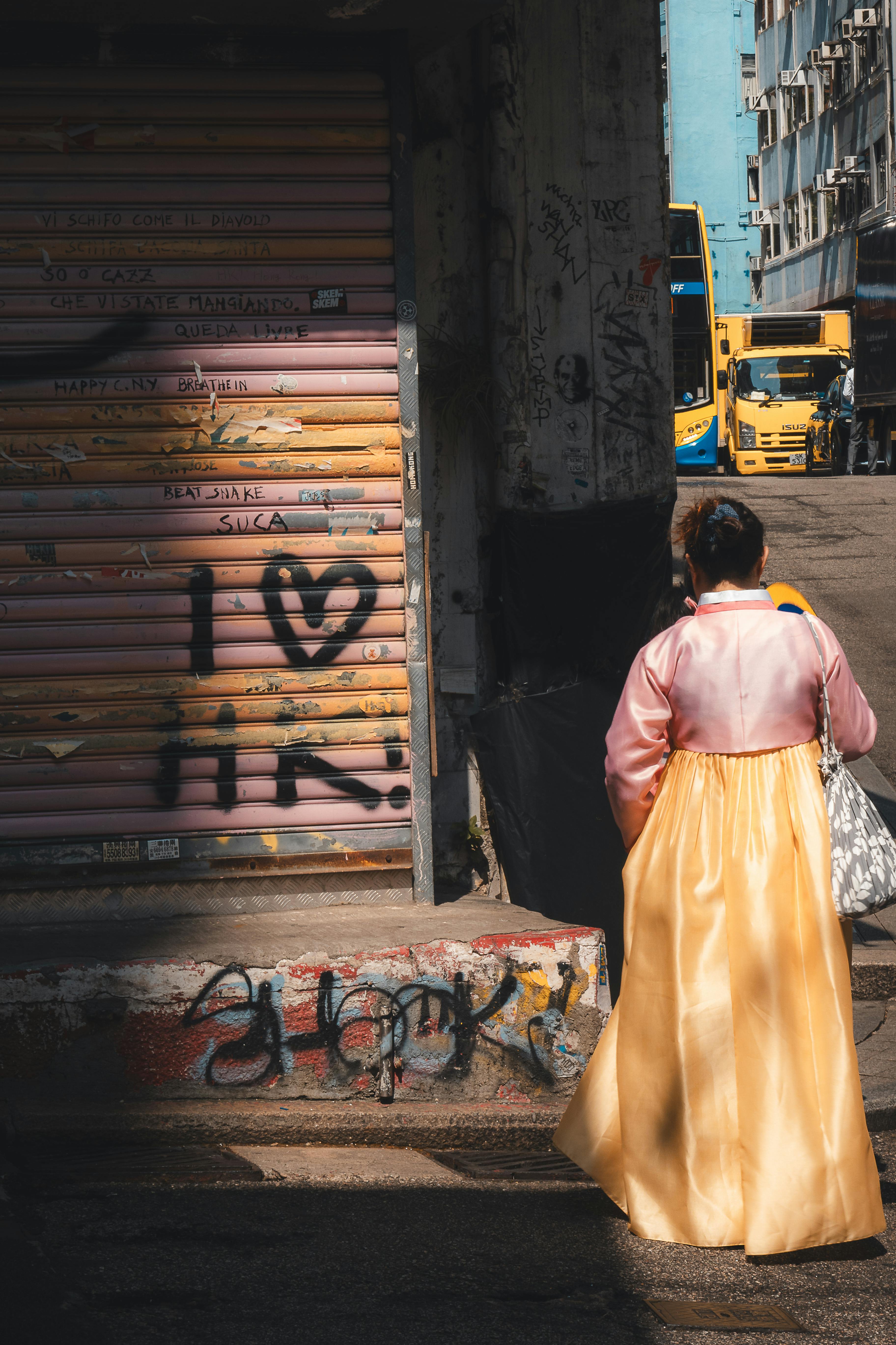 Ücretsiz Geleneksel kıyafetler giymiş bir kadın, Hong Kong'da hareketli bir sokak köşesinden geçerken, kentsel kültürü yansıtıyor. Stok Fotoğraflar