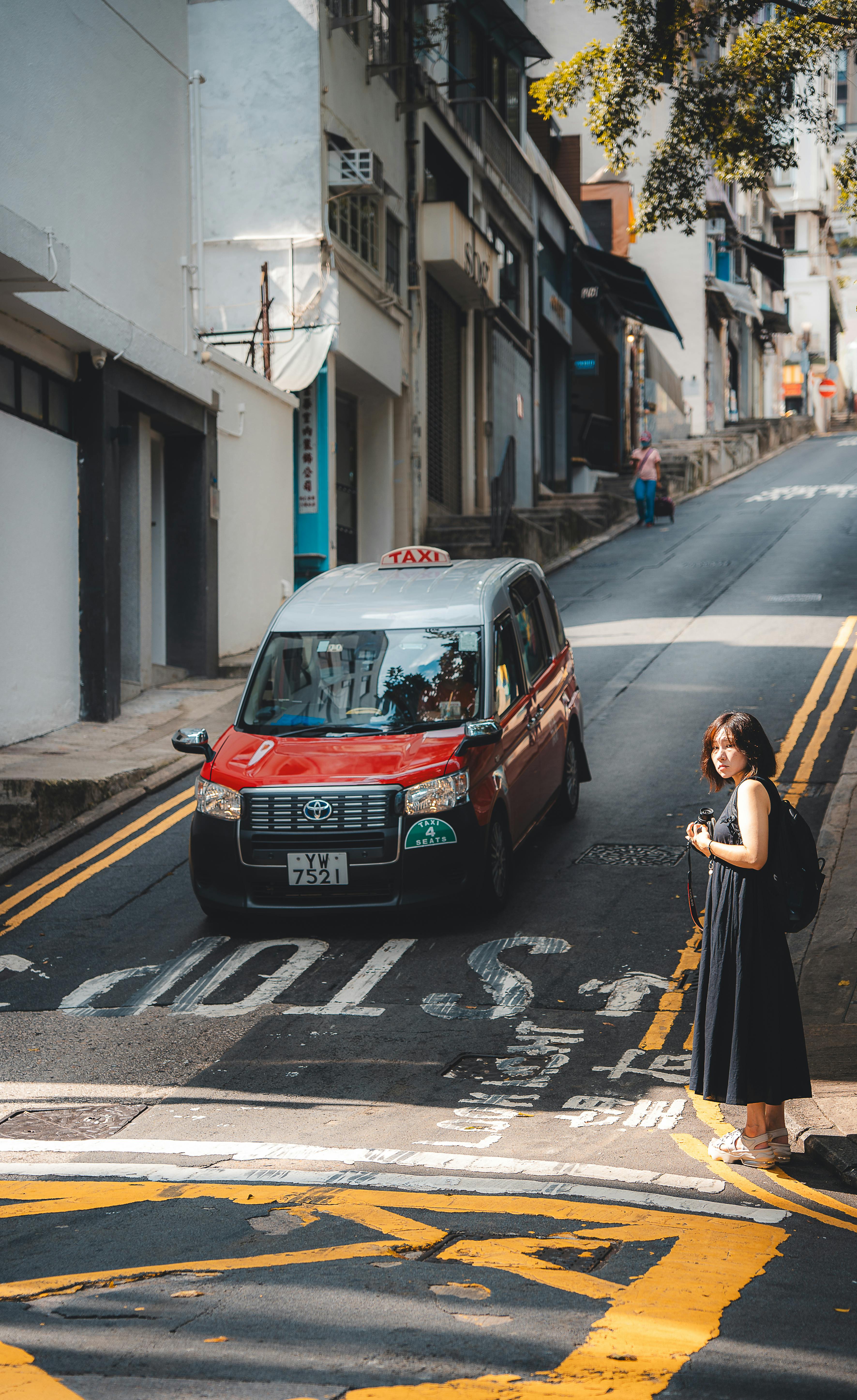 ingyenes Hongkong élénk utcaképe egy piros taxival és gyalogosokkal egy napsütéses napon. Stockfotó