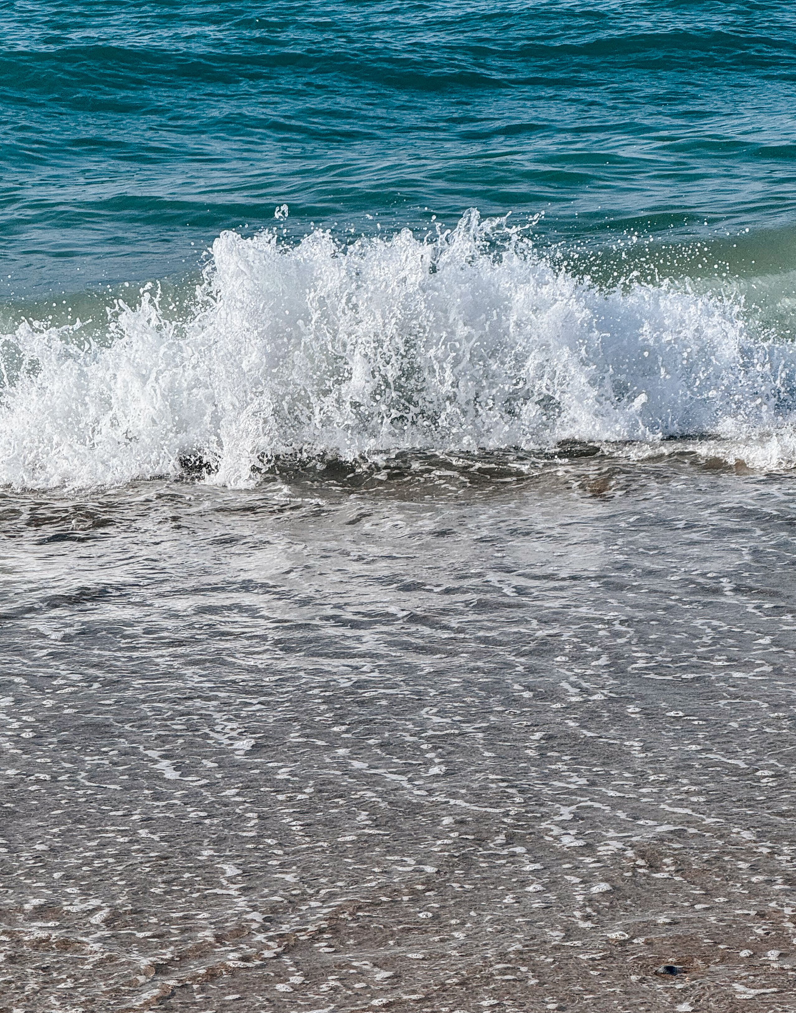 Fotomural Olas vibrantes del mar rompiendo en una playa de arena, capturando la esencia de un día de verano.