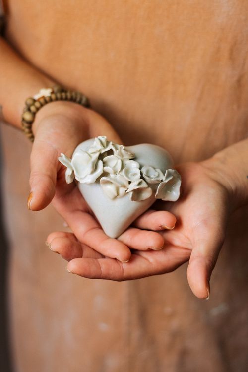 Free Artisan's hand holding a handmade ceramic heart with intricate floral design, symbolizing love and craftsmanship. Stock Photo