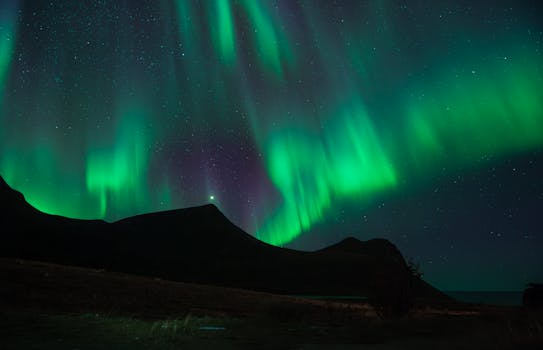 Dazzling Northern Lights illuminate the night sky over rugged mountains.