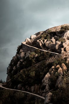 Discover the rugged beauty of a zigzag pathway carved into the rocky hills of Béjaïa, Algeria.