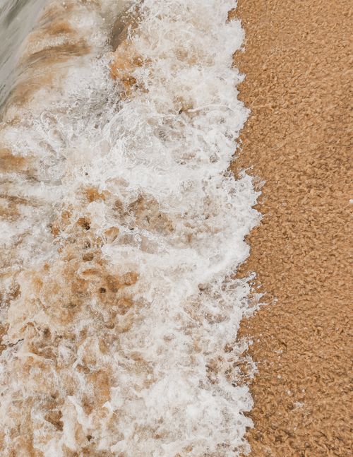 Free Dynamic close-up of a sea wave breaking on a sandy beach, showcasing the natural beauty of the ocean. Stock Photo