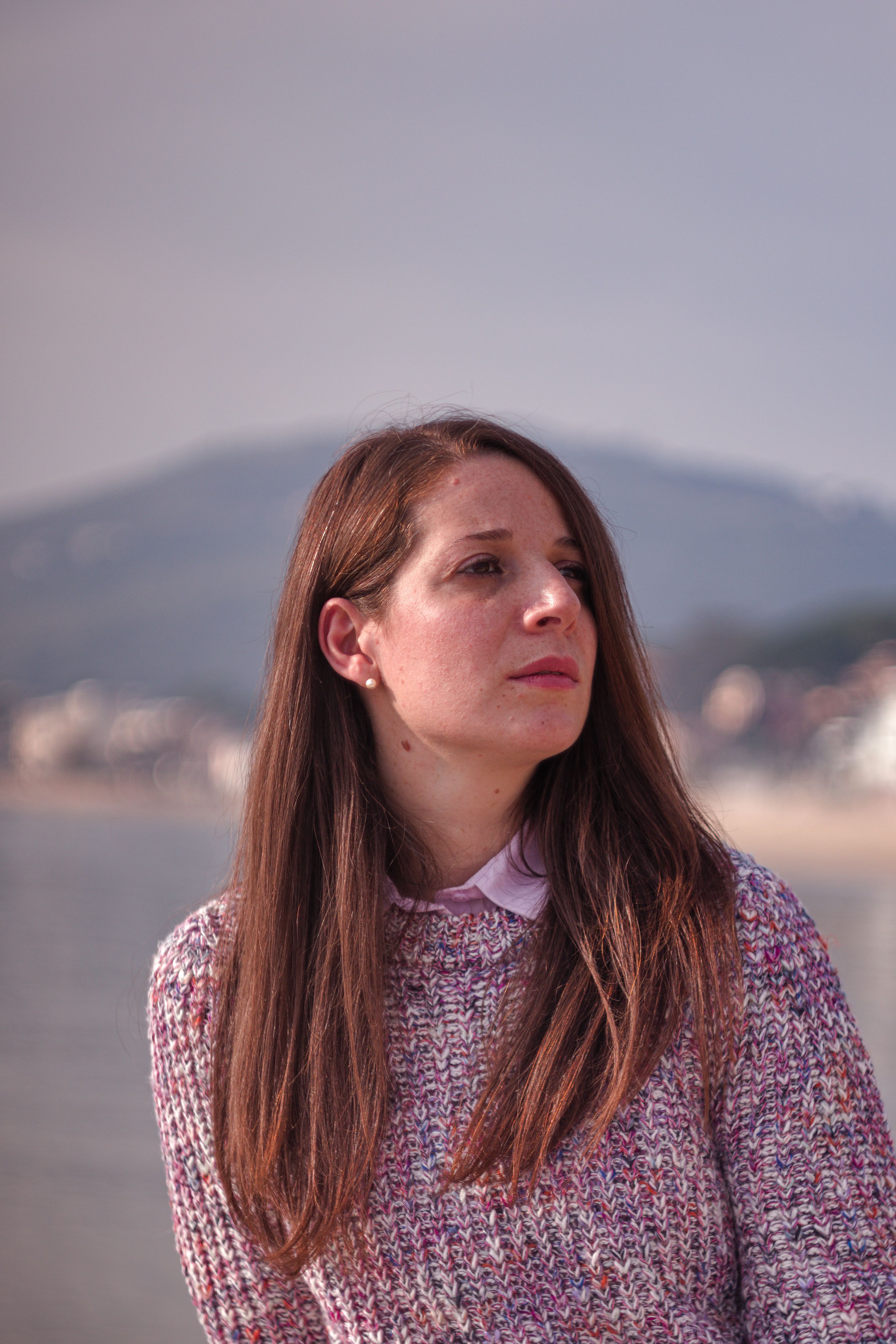 Portrait of a woman with long hair in a cozy sweater by the beach in Formia, Italy.