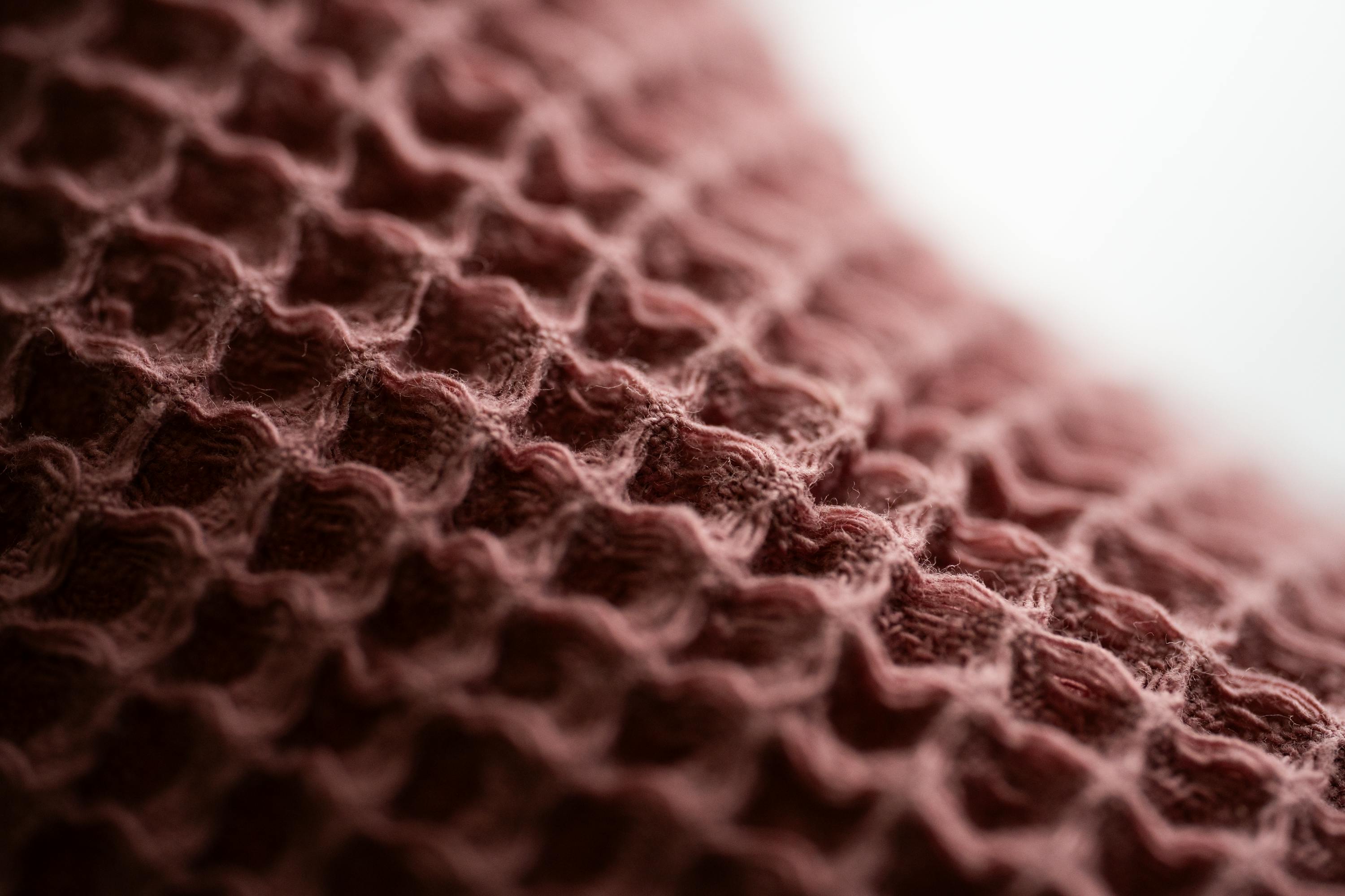 Безкоштовне Макрофотографія крупним планом, що підкреслює складний візерунок зі стільників на рожевій тканині. стокове фото