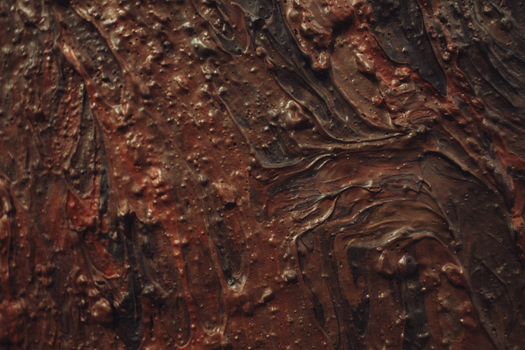 A close-up shot of textured abstract painting with earthy browns and reds.