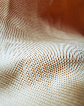 Detailed close-up of a light beige woven textile, showcasing texture and pattern.