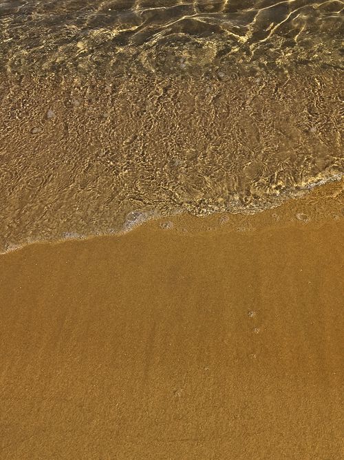 Free Close-up of gentle waves lapping on golden sandy beach at daytime. Stock Photo