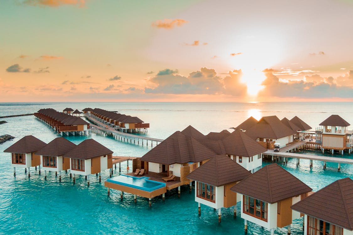 Free Brown and White Wooden Houses on Body of Water during Sunset Stock Photo