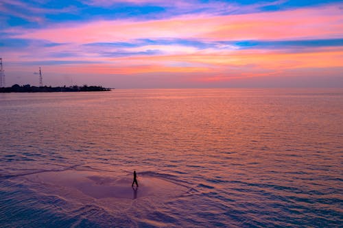 無料 日没時にビーチを歩く人のシルエット 写真素材