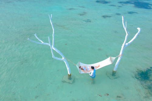 免費 躺在海灘上的白色吊床上的女人 圖庫相片