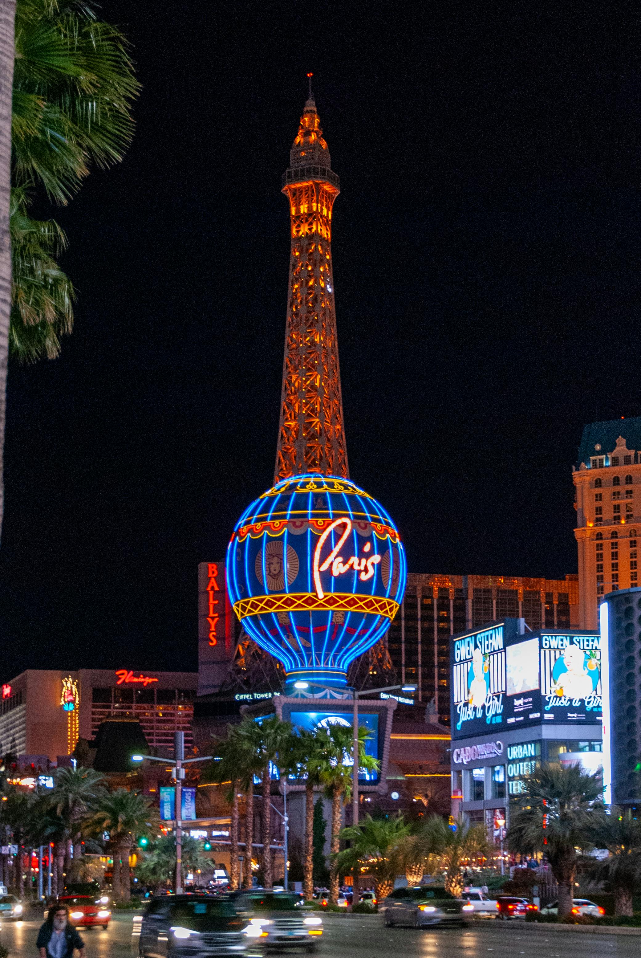 Night view of the Eiffel Tower replica and vibrant neon signs at Paris Las Vegas Hotel, Nevada.