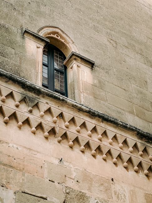 Arched window and ornate stonework on an old building facade in Malta.