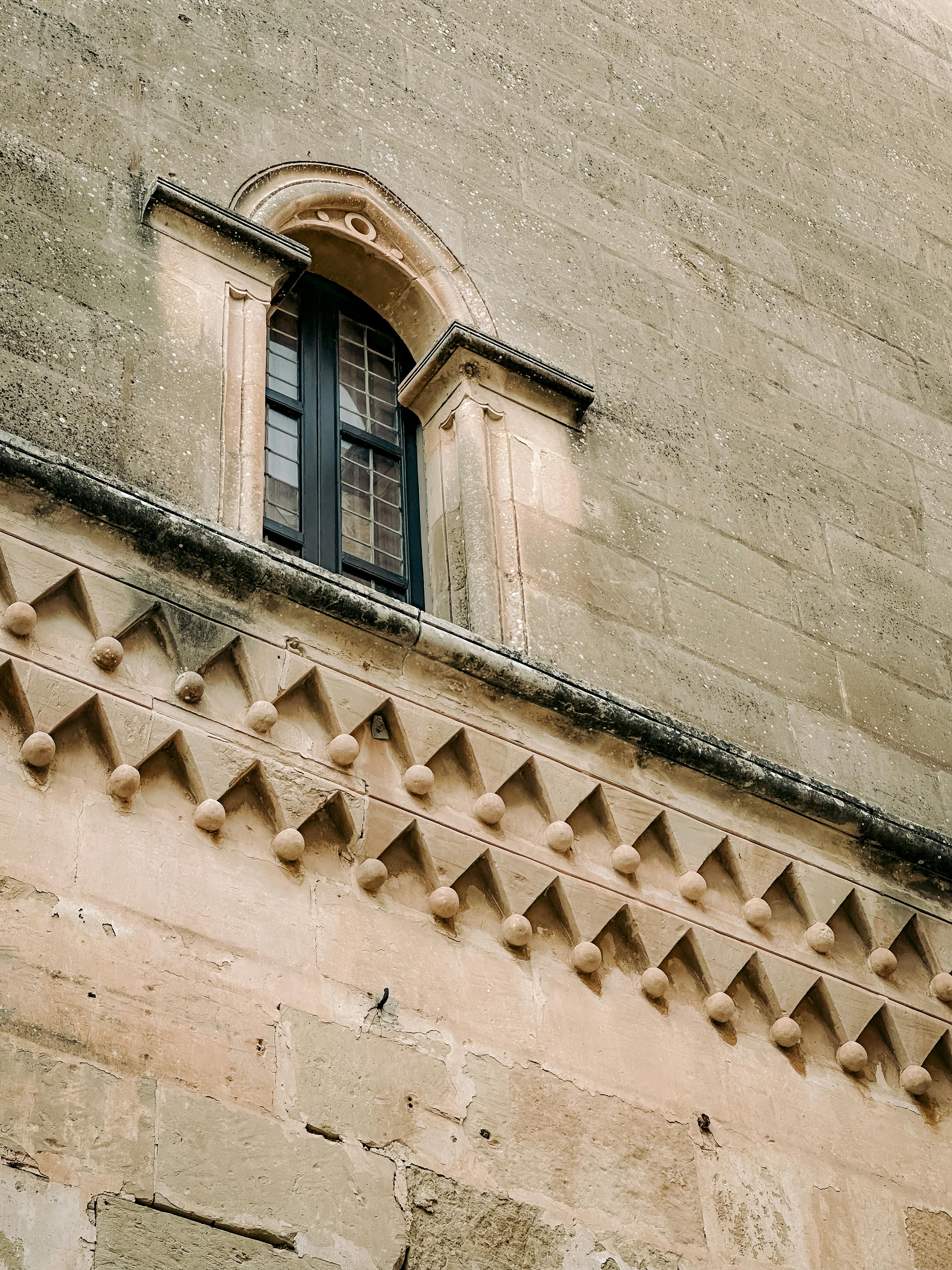 Free Arched window and ornate stonework on an old building facade in Malta. Stock Photo