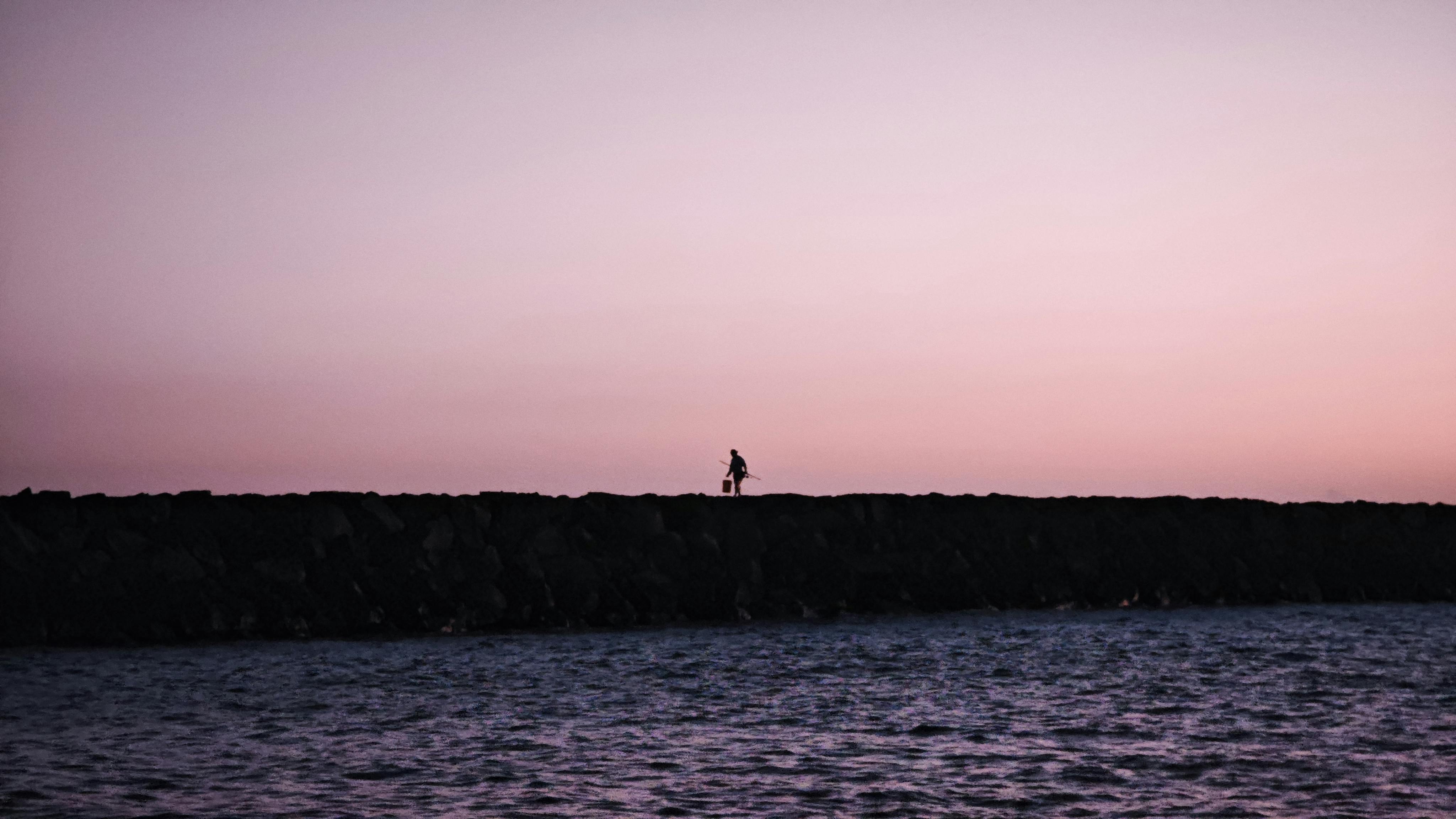 Безкоштовне Самотній рибалка на скельній стіні на заході сонця на Гаваях, створюючи безтурботний та мальовничий пейзаж. стокове фото