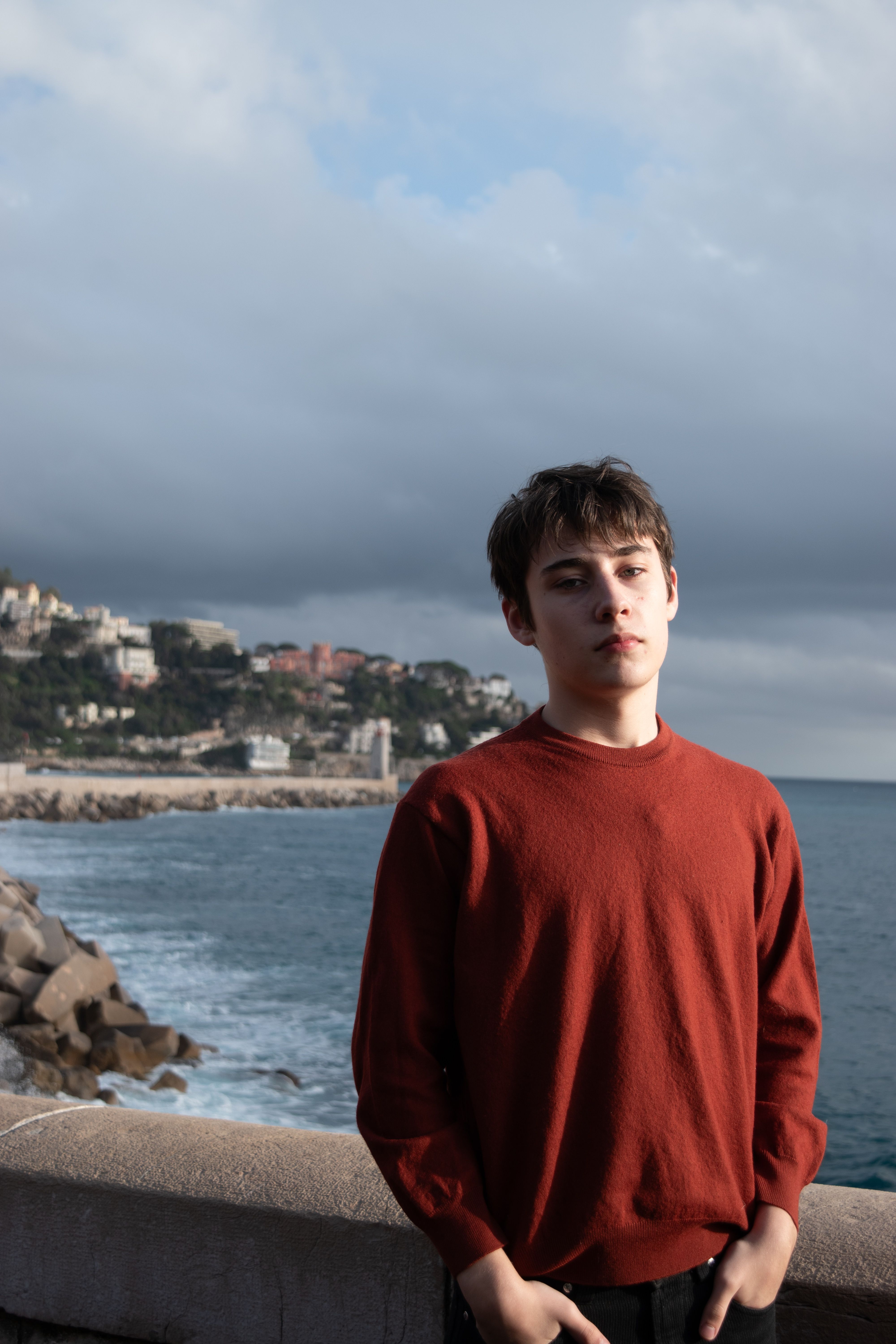 Portrait of a young man standing by the sea in Nice, France, with a moody sky.