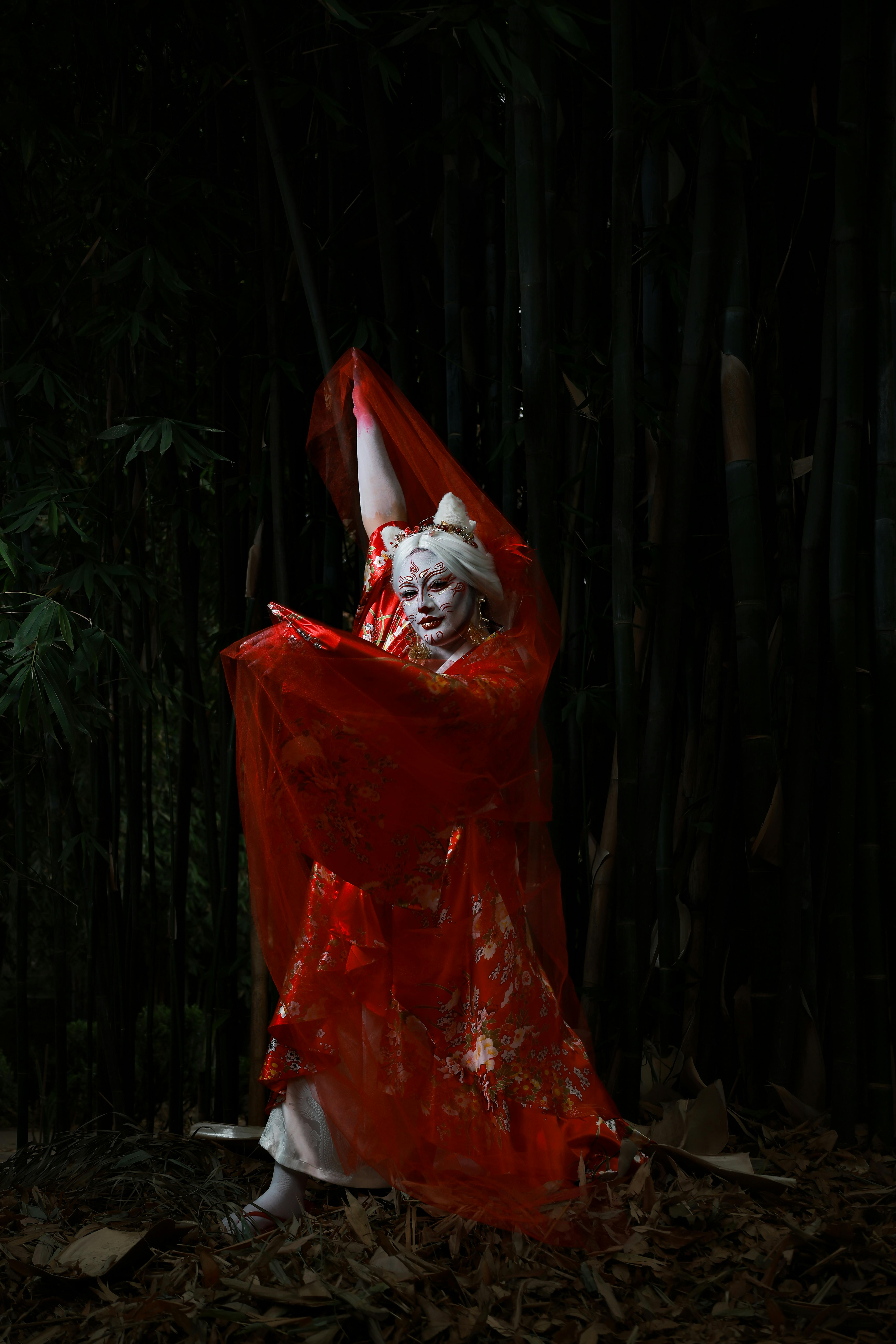 Gratis Potret artistik seorang penampil tradisional Jepang dengan pakaian berwarna cerah di tengah hutan bambu. Foto Stok