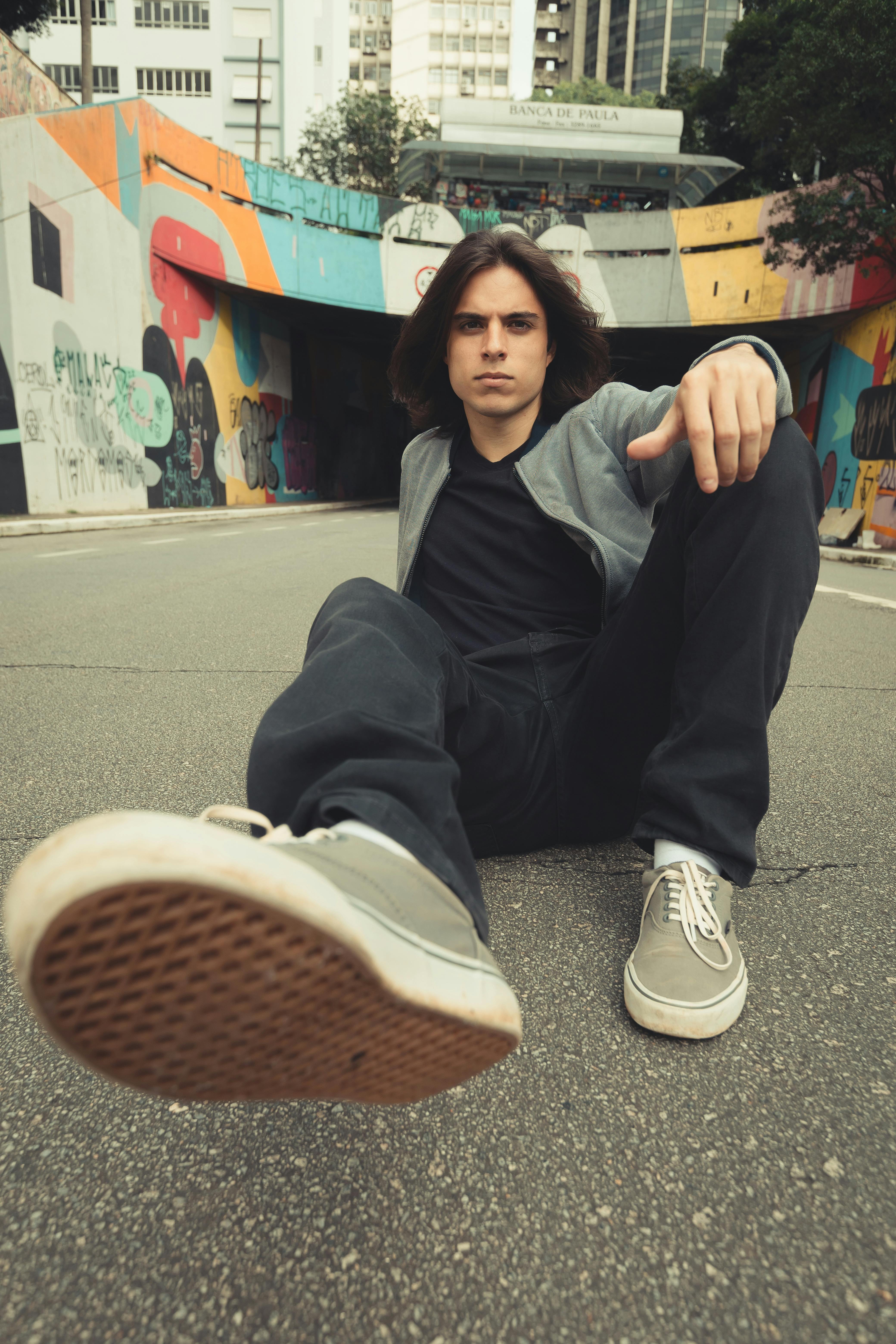 Dynamic street portrait of a young man sitting in an urban São Paulo setting.