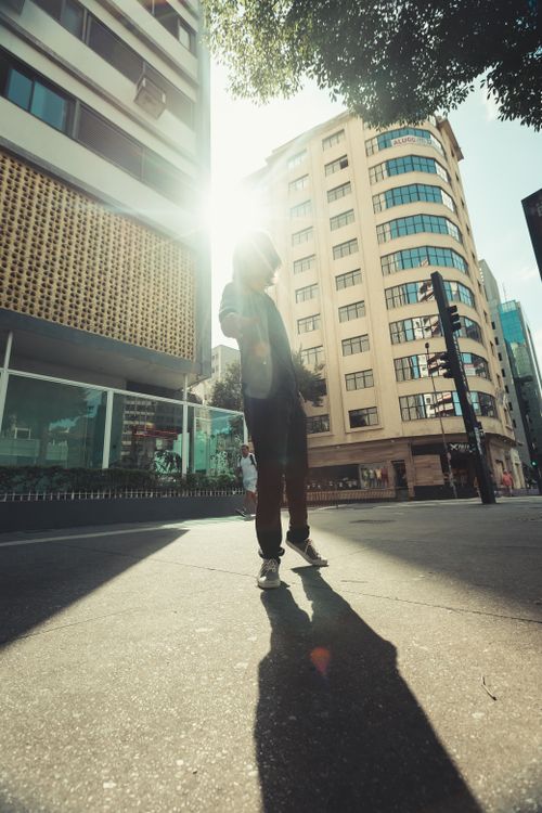 Free Street portrait of a man in São Paulo, capturing the vibrant cityscape and dramatic sunlight. Stock Photo