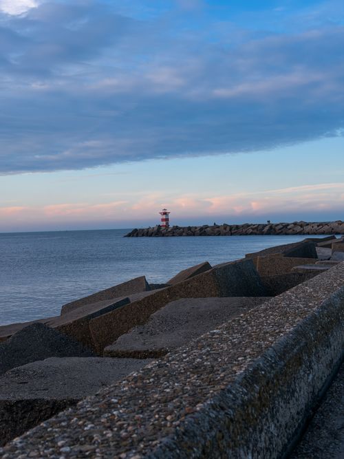 Free A picturesque lighthouse near a coastal breakwater in The Hague, Netherlands. Stock Photo