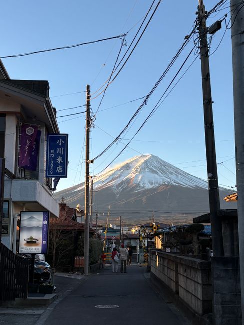 A picturesque view of Mount Fuji from a quaint Japanese street at dusk, capturing cultural architecture.