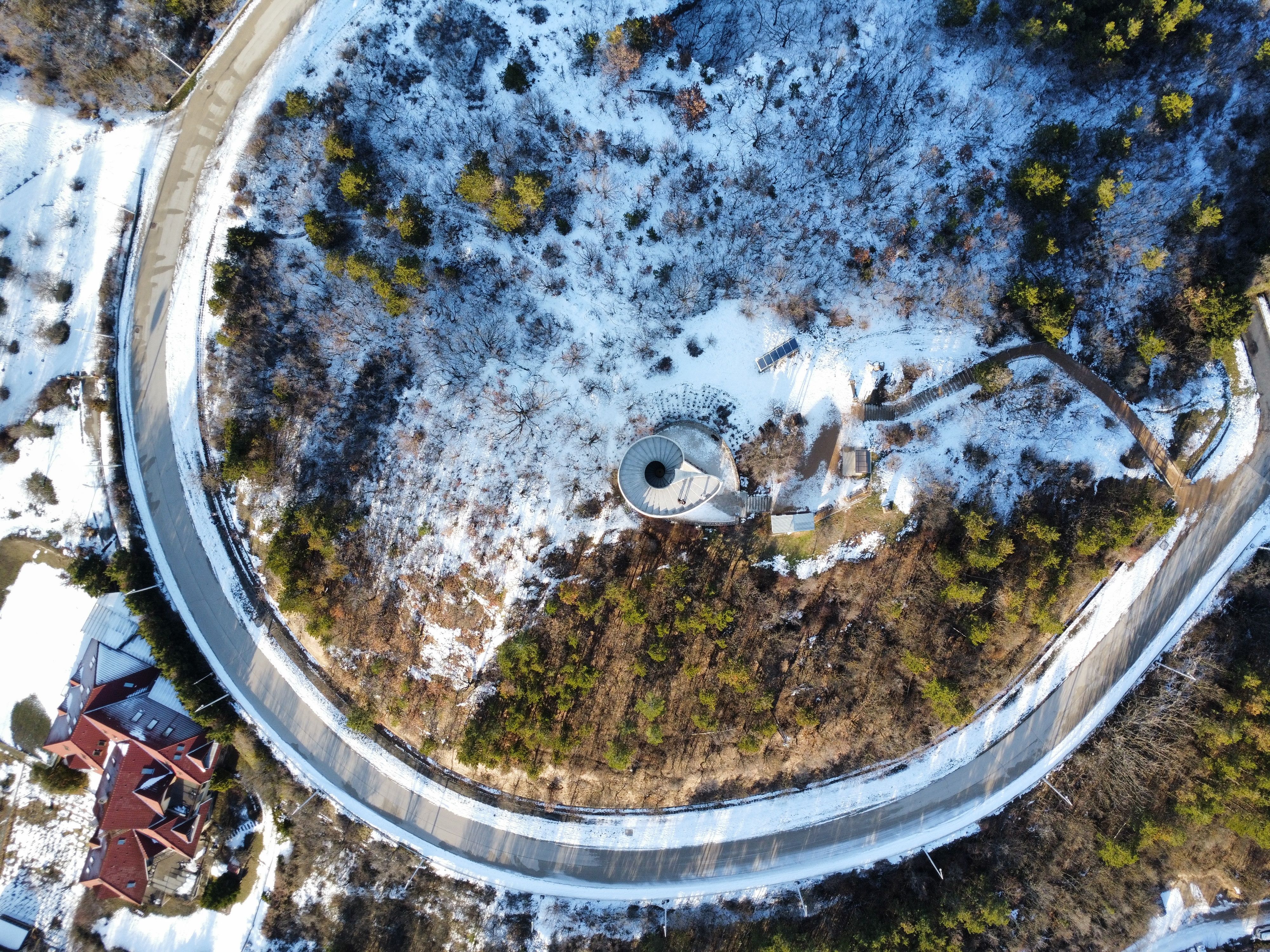 A stunning aerial shot of a spiral tower in a snowy forest during winter, showcasing the surrounding landscape.