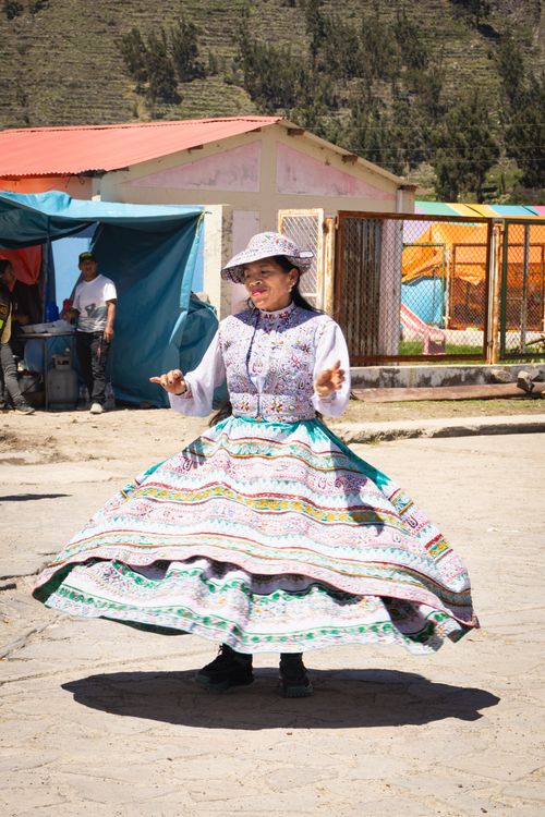 Free Woman in vibrant traditional attire dances joyfully in the sunlit streets of Chivay, Peru. Stock Photo