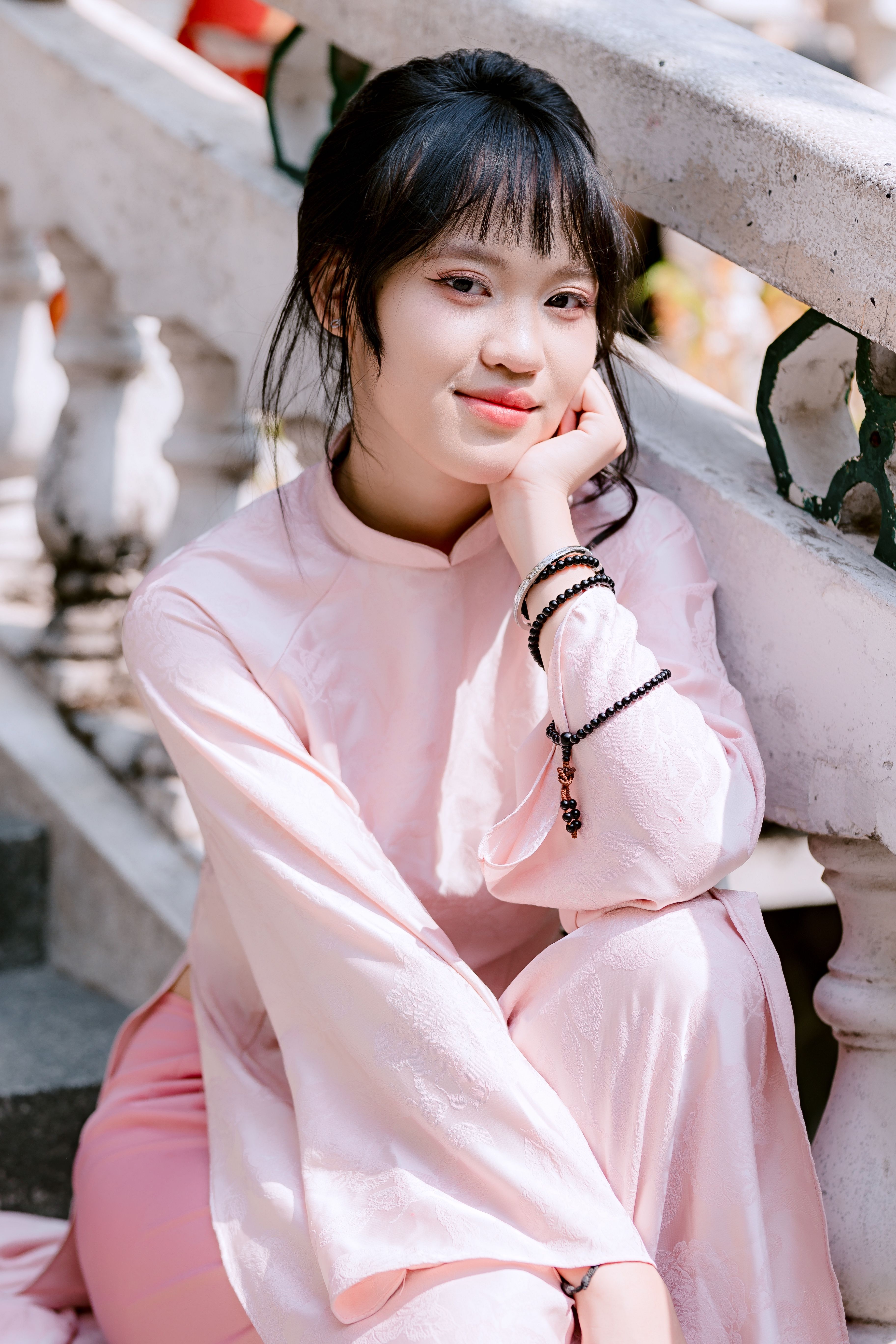 Portrait of a young woman in a pink traditional dress sitting outdoors.