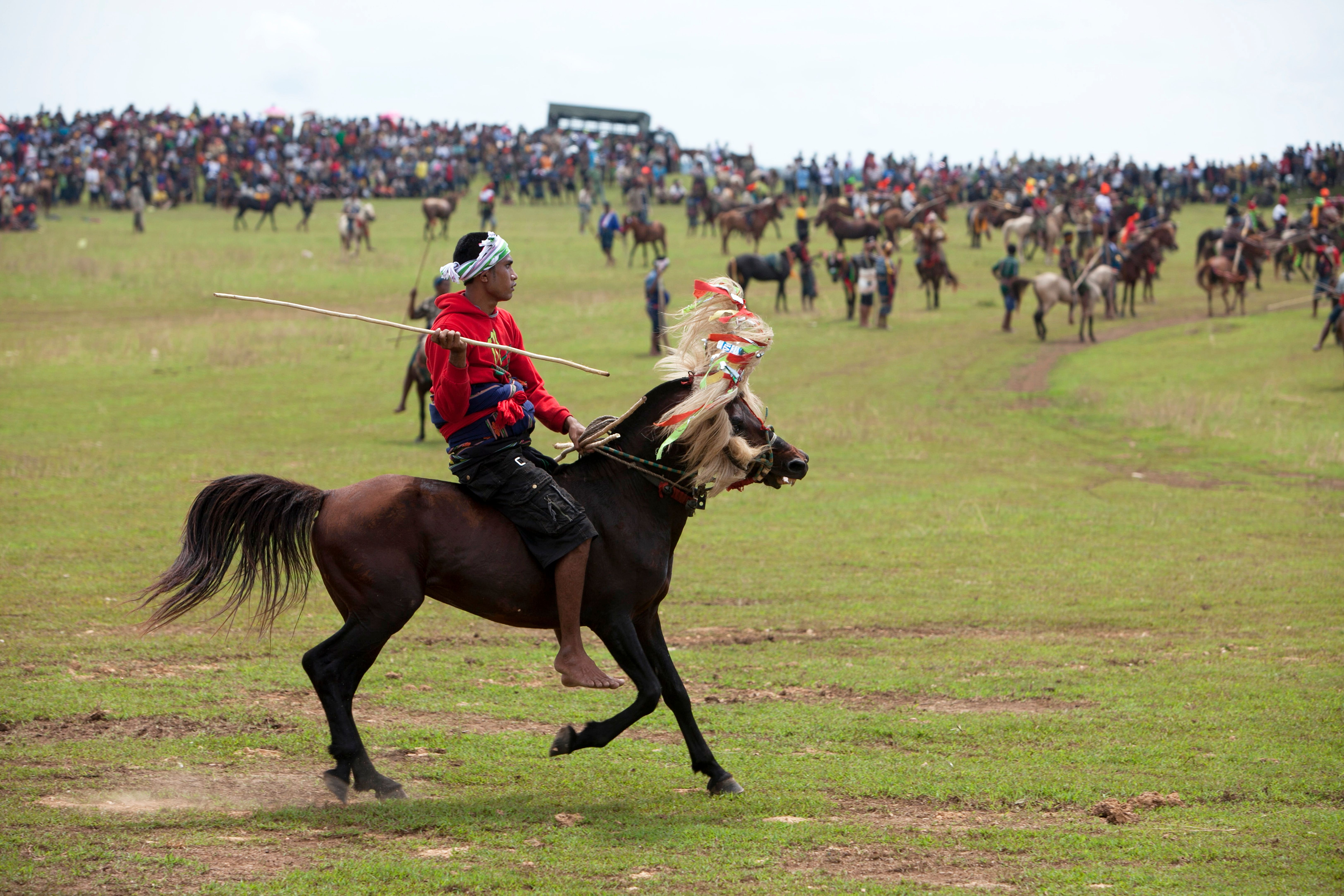 A vibrant traditional equestrian event with a large crowd and horseback riders in colorful attire.