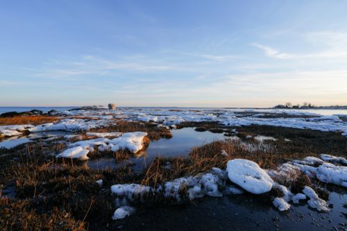 Free Scenic view of a snowy shoreline during sunset, capturing the serene beauty of winter’s end. Stock Photo