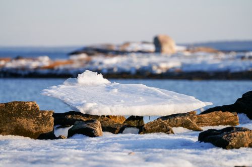 Free Serene winter scene with ice formation on rocks by the coast under a clear blue sky. Stock Photo